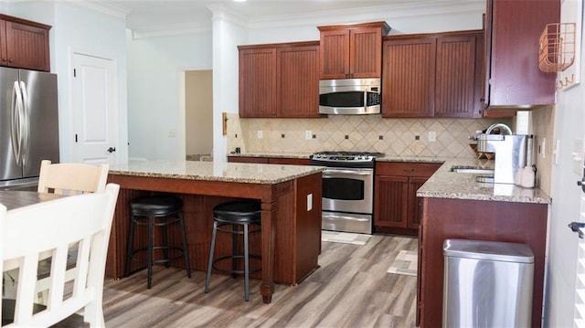 kitchen featuring sink, light hardwood / wood-style flooring, stainless steel appliances, light stone countertops, and crown molding