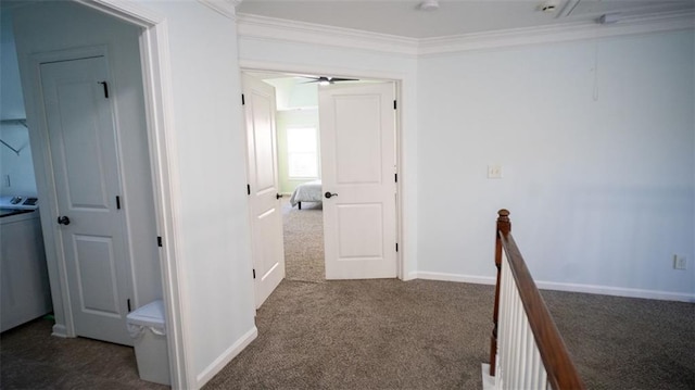 hallway featuring washer / clothes dryer, crown molding, and dark colored carpet