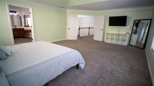 bedroom featuring dark colored carpet, crown molding, and connected bathroom