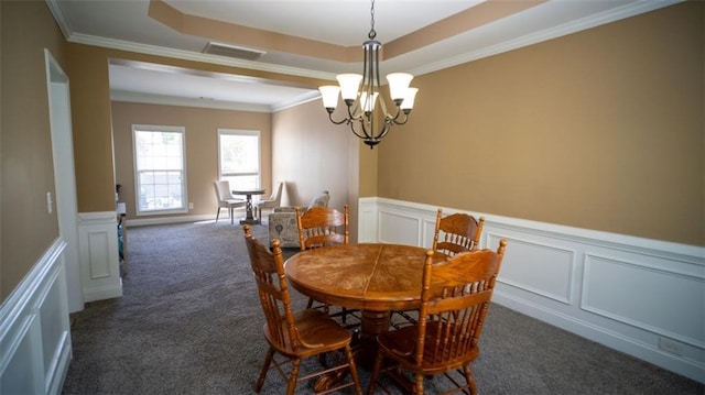 dining space with dark carpet, a tray ceiling, and ornamental molding