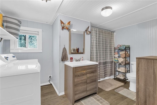 bathroom featuring curtained shower, toilet, wood finished floors, washer and dryer, and vanity