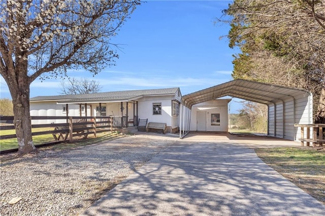 view of front facade with a detached carport, driveway, and fence