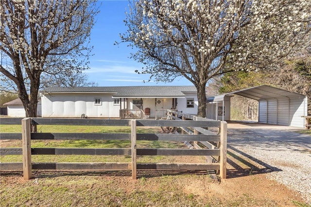 single story home featuring a carport, covered porch, driveway, and a fenced front yard