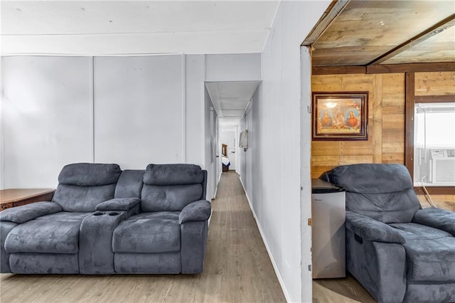 living area featuring baseboards, wood finished floors, and wood walls