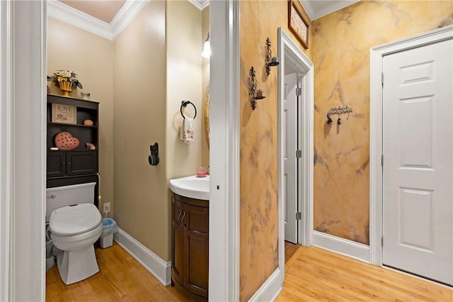 bathroom featuring toilet, ornamental molding, wood finished floors, and vanity