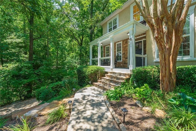 doorway to property with a porch and stucco siding