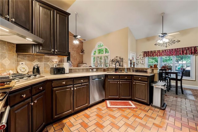 kitchen with appliances with stainless steel finishes, a peninsula, light countertops, under cabinet range hood, and a sink