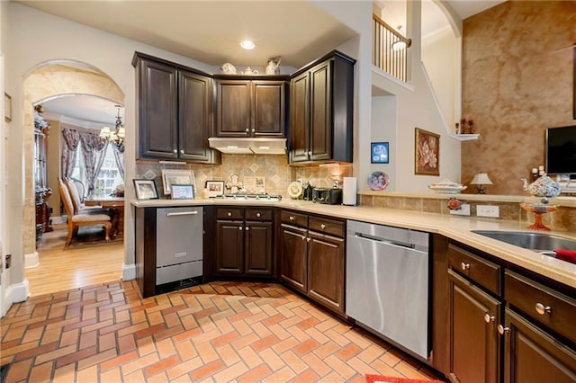 kitchen featuring appliances with stainless steel finishes, light countertops, under cabinet range hood, and dark brown cabinets