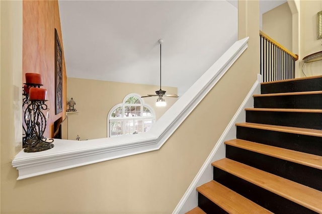 stairway featuring lofted ceiling and ceiling fan