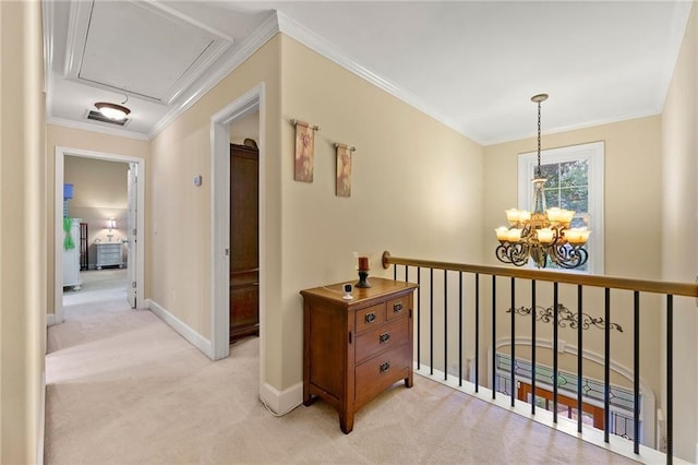 corridor featuring light carpet, ornamental molding, attic access, and an inviting chandelier