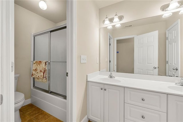 bathroom featuring double vanity, visible vents, toilet, enclosed tub / shower combo, and a sink