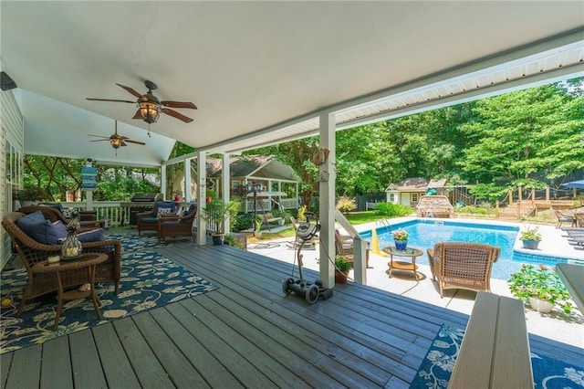 wooden terrace featuring ceiling fan, outdoor lounge area, fence, an outdoor structure, and an outdoor pool