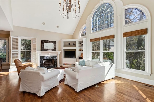 living room featuring wood-type flooring, high vaulted ceiling, a chandelier, and a fireplace