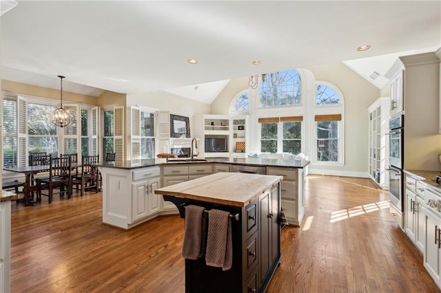 kitchen featuring white cabinetry, vaulted ceiling, kitchen peninsula, and a kitchen island