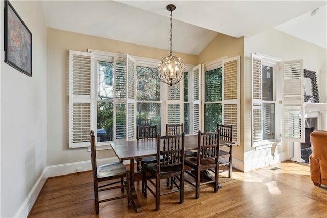 dining space featuring vaulted ceiling, wood-type flooring, and a chandelier