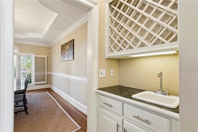 bar featuring sink, ornamental molding, dark hardwood / wood-style floors, tile counters, and white cabinets