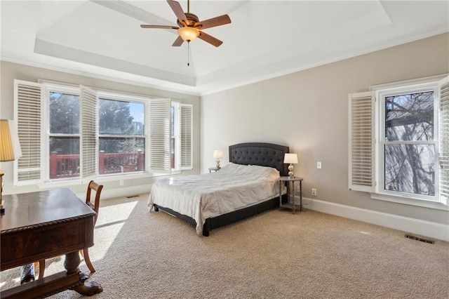 carpeted bedroom with ceiling fan, ornamental molding, and a tray ceiling