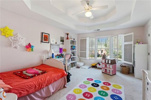 carpeted bedroom featuring ceiling fan and a tray ceiling