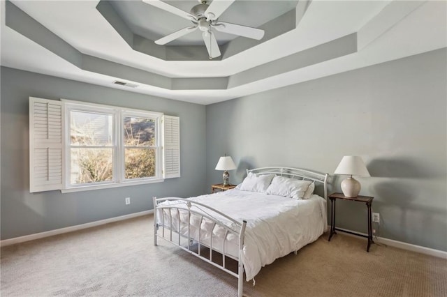 bedroom with ceiling fan, carpet flooring, and a tray ceiling