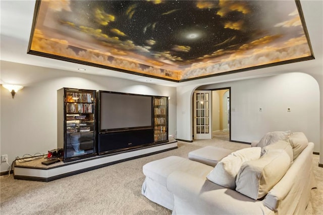 carpeted cinema room featuring a raised ceiling