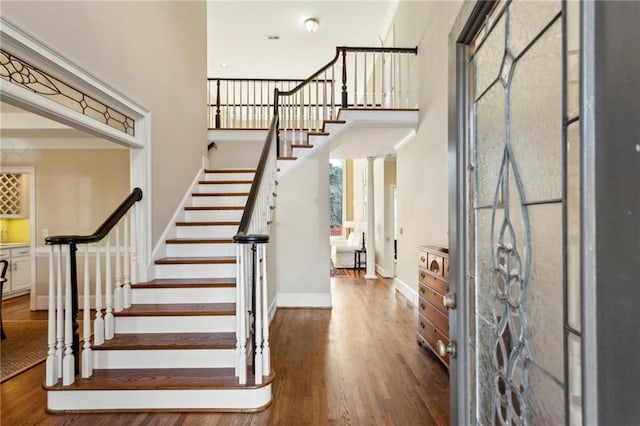 foyer entrance with ornamental molding, dark hardwood / wood-style flooring, and a high ceiling