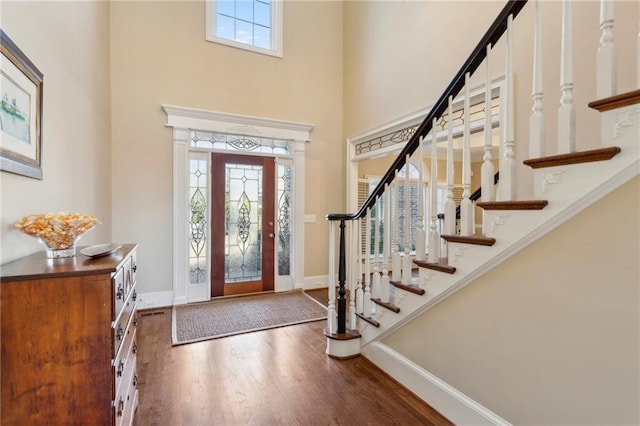 entryway featuring a towering ceiling and dark hardwood / wood-style flooring