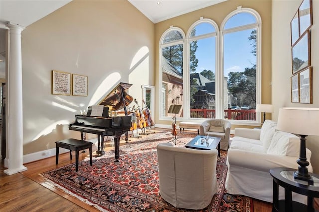 sitting room featuring ornate columns, wood-type flooring, and vaulted ceiling