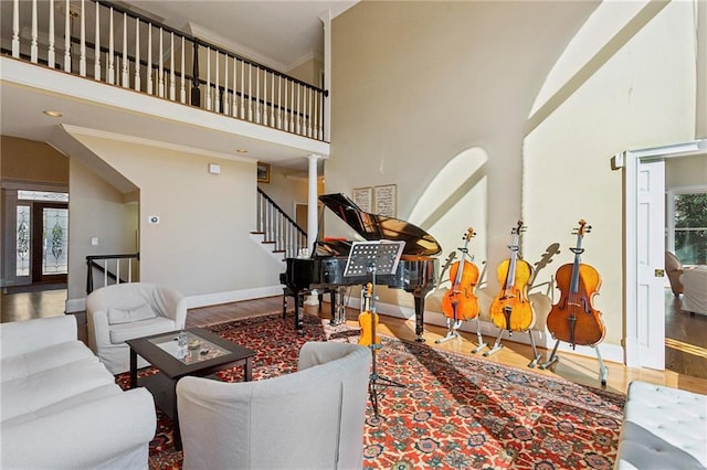 living room with a towering ceiling, ornamental molding, and hardwood / wood-style floors