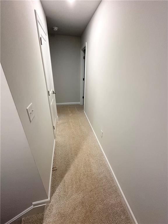 hall featuring carpet flooring and baseboards