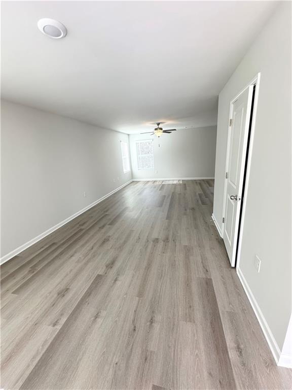 spare room with a ceiling fan, wood finished floors, and baseboards