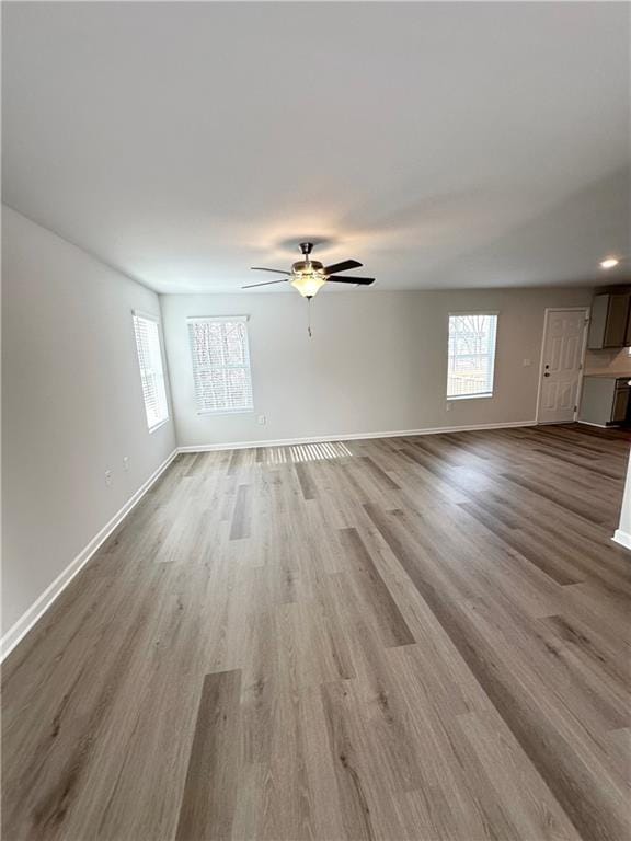 unfurnished living room with baseboards, wood finished floors, and a ceiling fan