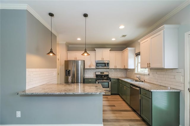 kitchen with crown molding, a peninsula, appliances with stainless steel finishes, decorative light fixtures, and backsplash