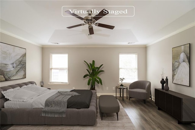 bedroom with a raised ceiling, wood finished floors, ornamental molding, and visible vents