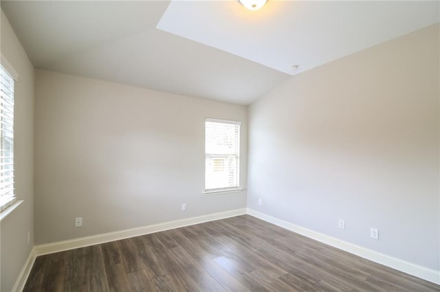 spare room with baseboards, dark wood-style floors, and vaulted ceiling
