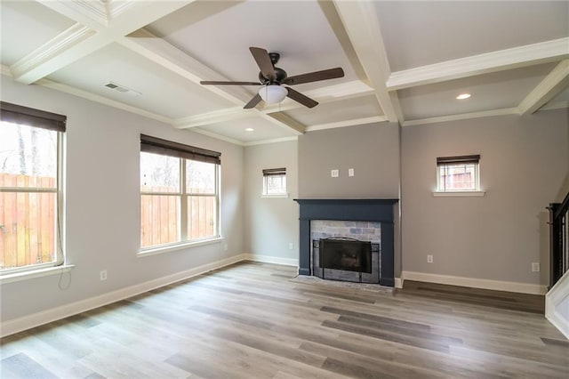 unfurnished living room with a fireplace, plenty of natural light, beam ceiling, and coffered ceiling