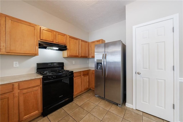 kitchen featuring under cabinet range hood, black gas range, stainless steel fridge, and light countertops