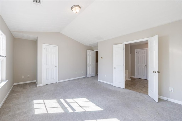 unfurnished bedroom with visible vents, lofted ceiling, light colored carpet, and baseboards