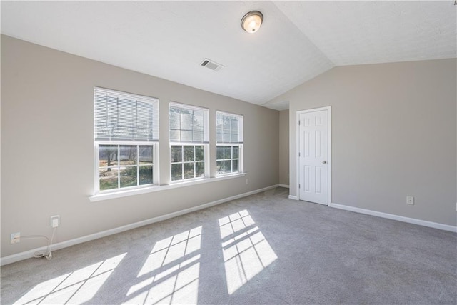 spare room with visible vents, carpet flooring, baseboards, and vaulted ceiling