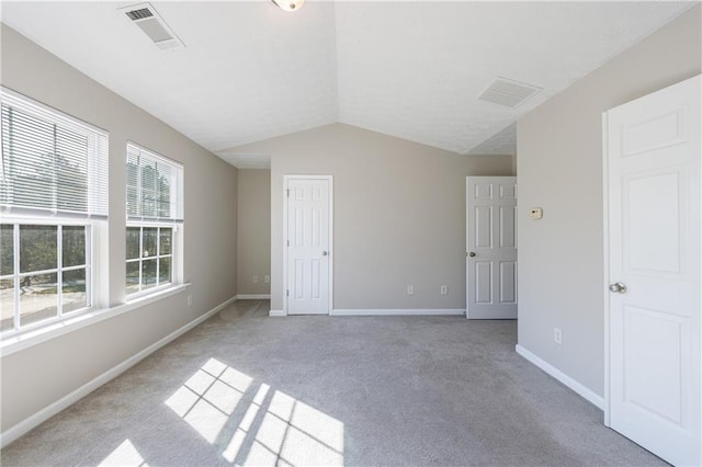 unfurnished bedroom with visible vents, light colored carpet, baseboards, and vaulted ceiling