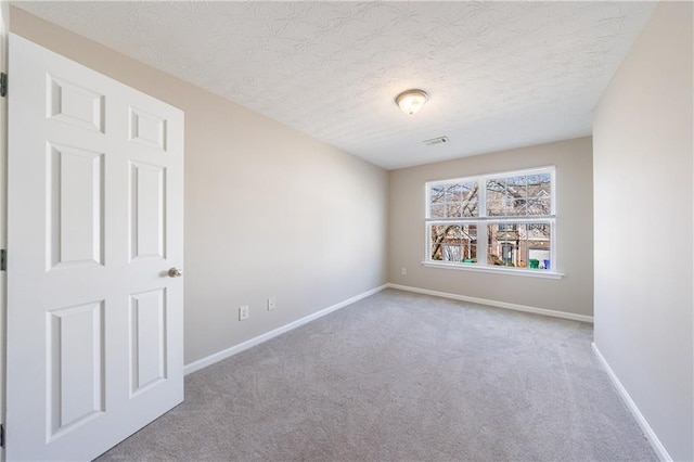 carpeted empty room featuring visible vents, baseboards, and a textured ceiling