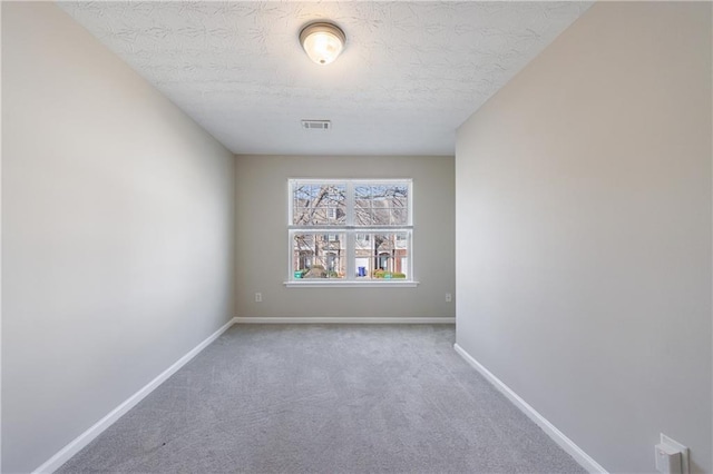 empty room featuring visible vents, a textured ceiling, carpet, and baseboards