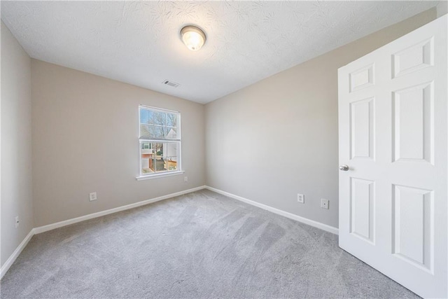 carpeted spare room featuring visible vents, a textured ceiling, and baseboards