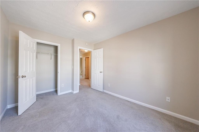 unfurnished bedroom featuring carpet flooring, baseboards, a closet, and a textured ceiling