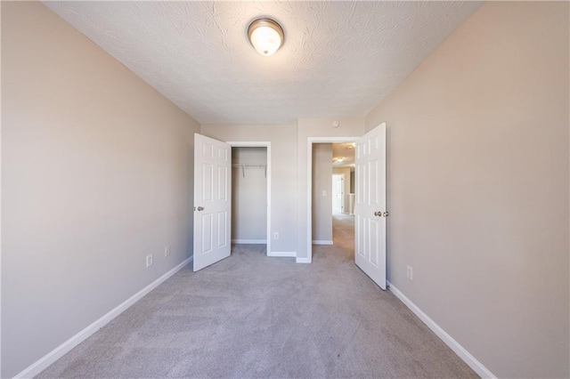 unfurnished bedroom with a closet, a textured ceiling, carpet, and baseboards