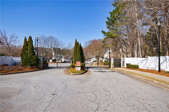 view of street featuring curbs, street lights, a gated entry, and a gate