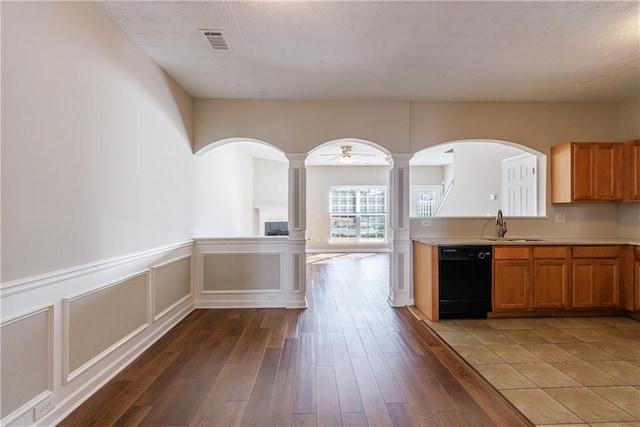 kitchen with light countertops, black dishwasher, wood finished floors, and visible vents