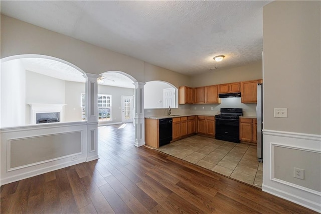 kitchen featuring ornate columns, a sink, black appliances, light countertops, and under cabinet range hood