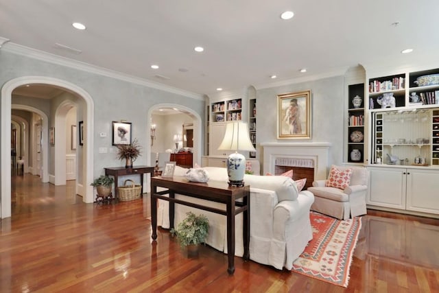 living room featuring built in features, dark hardwood / wood-style floors, and crown molding