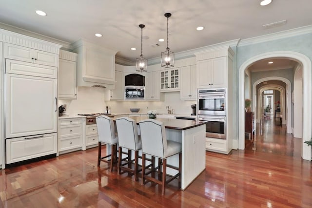 kitchen featuring decorative light fixtures, dark wood-type flooring, a center island, double oven, and a kitchen breakfast bar