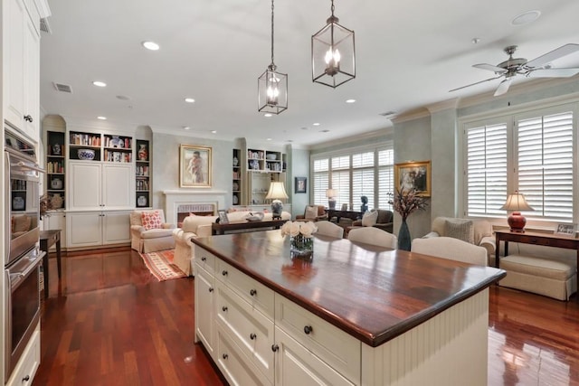 kitchen featuring ornamental molding, ceiling fan with notable chandelier, a kitchen island, and dark hardwood / wood-style flooring